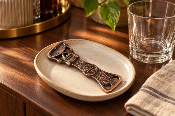 AI styling illustration of a bronze-tone Copper Bones skull-key bottle opener on a ceramic dish
