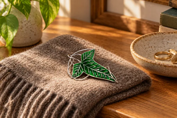 AI styling illustration of The Fellowship’s leaf brooch on folded knitwear beside an accessory dish